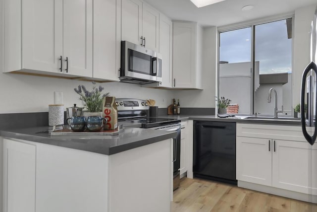 kitchen with appliances with stainless steel finishes, sink, light hardwood / wood-style flooring, and white cabinets