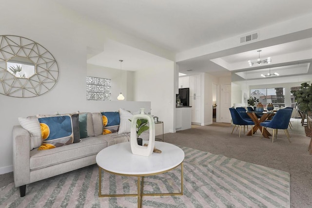 carpeted living room featuring an inviting chandelier