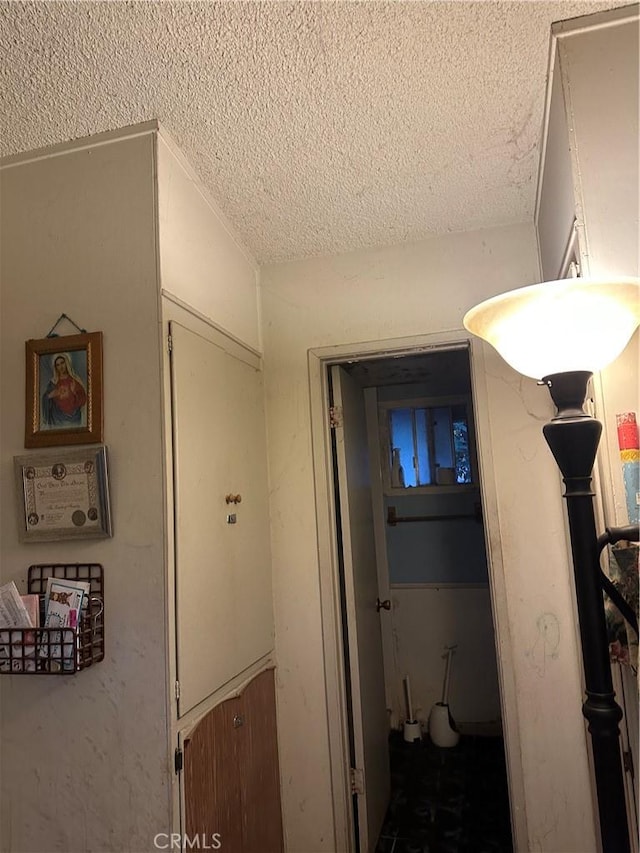 corridor featuring lofted ceiling and a textured ceiling