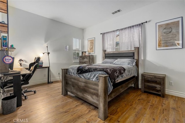 bedroom featuring baseboards, visible vents, and wood finished floors