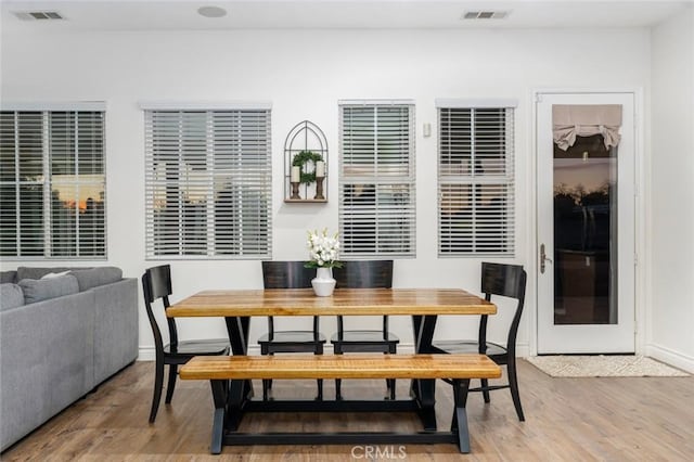 dining space with baseboards, breakfast area, visible vents, and wood finished floors