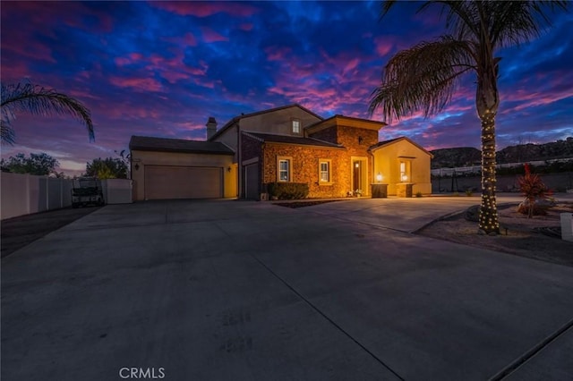 view of front of house with fence, stucco siding, an attached garage, and driveway