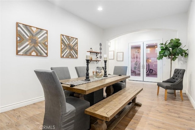 dining room with french doors, recessed lighting, arched walkways, baseboards, and light wood-type flooring