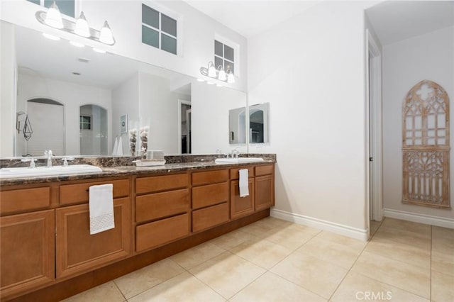 full bathroom featuring double vanity, baseboards, a sink, and tile patterned flooring