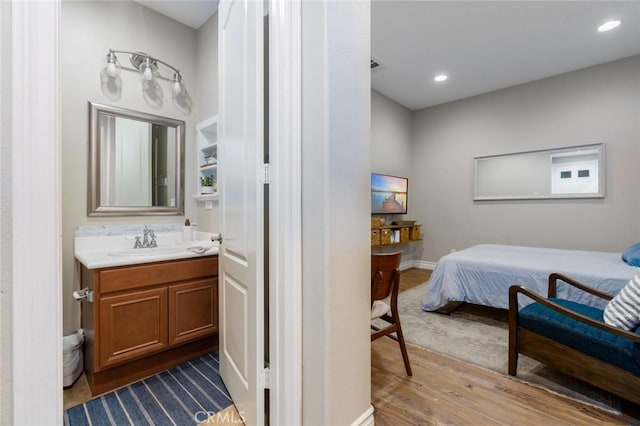 bathroom with vanity, baseboards, wood finished floors, and recessed lighting