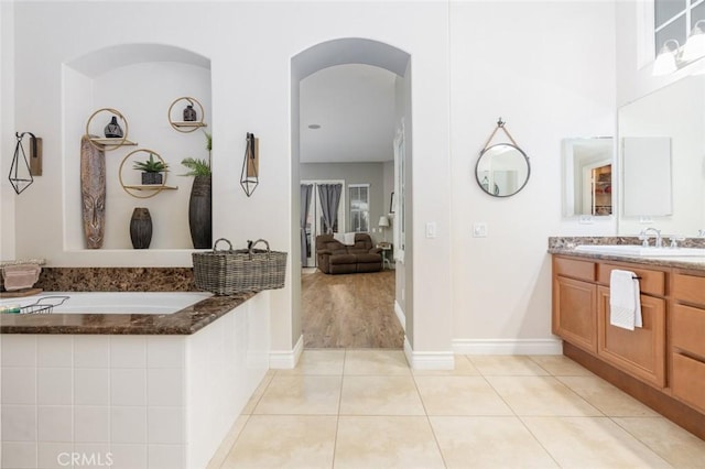 full bathroom with a relaxing tiled tub, vanity, and tile patterned floors