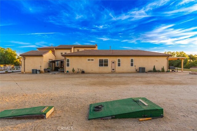 back of house featuring stucco siding and central air condition unit