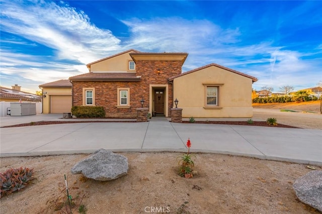 view of front of property with driveway, stucco siding, stone siding, and a garage