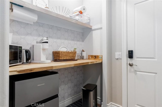 interior space with decorative backsplash, butcher block countertops, and stainless steel fridge