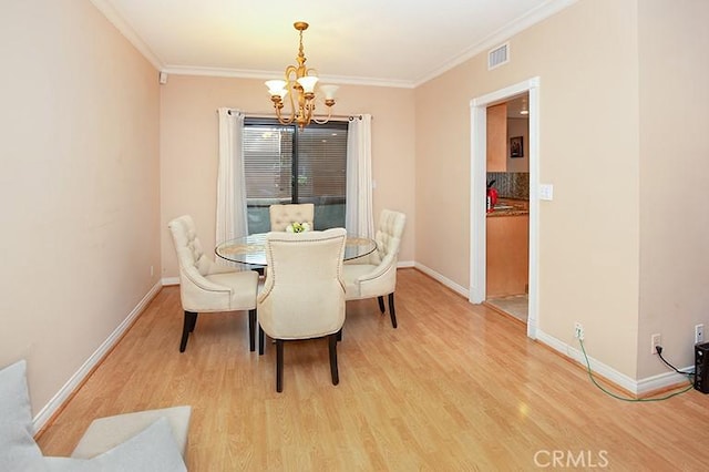 dining space featuring crown molding, a notable chandelier, and light hardwood / wood-style floors