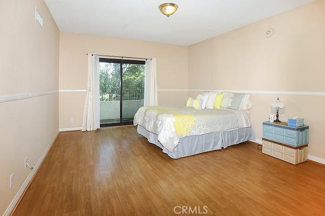 bedroom with access to outside, baseboards, and wood finished floors