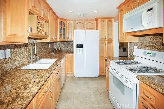 kitchen featuring a sink, white appliances, stone countertops, decorative backsplash, and glass insert cabinets