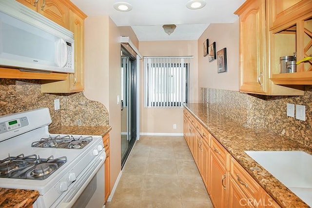 kitchen featuring sink, light tile patterned floors, white appliances, light stone countertops, and decorative backsplash