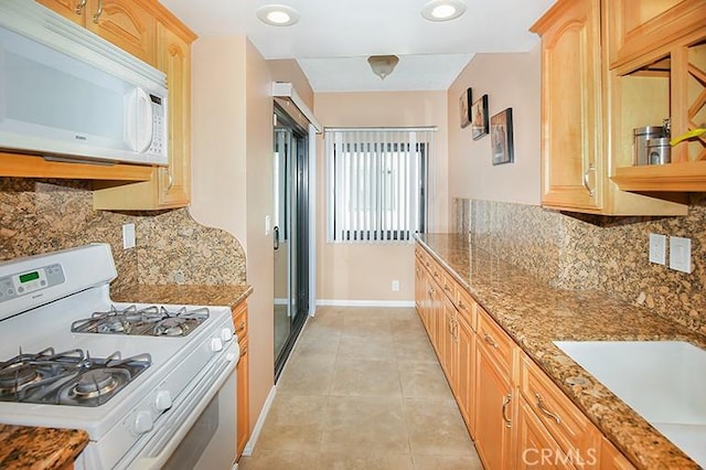 kitchen with baseboards, backsplash, light tile patterned floors, and white appliances