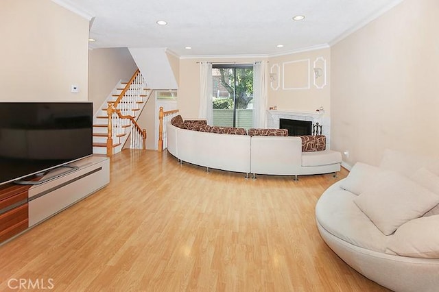living room featuring stairway, ornamental molding, a brick fireplace, and wood finished floors