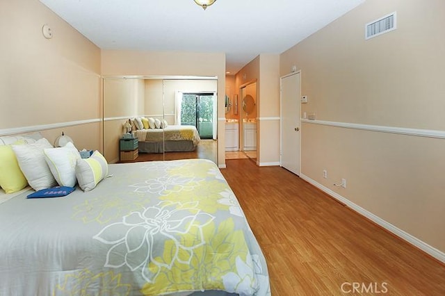 bedroom featuring baseboards, visible vents, and wood finished floors