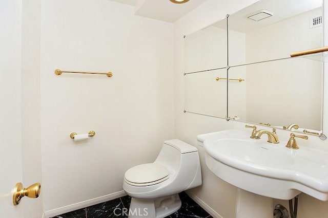bathroom with baseboards, marble finish floor, and toilet