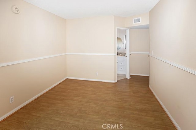 empty room featuring visible vents, baseboards, and wood finished floors