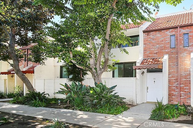 view of front facade with stucco siding, fence, and brick siding