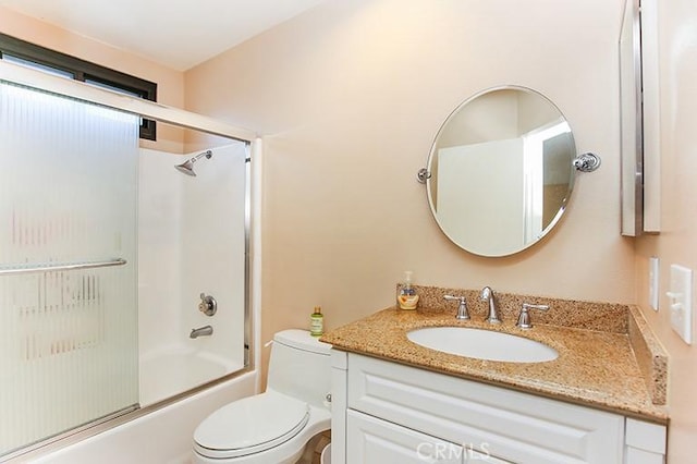 full bathroom with enclosed tub / shower combo, vanity, and toilet