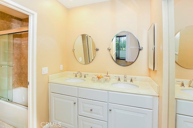 full bathroom featuring double vanity, enclosed tub / shower combo, and a sink