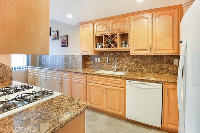 kitchen with white appliances, dark stone counters, sink, and light tile patterned floors