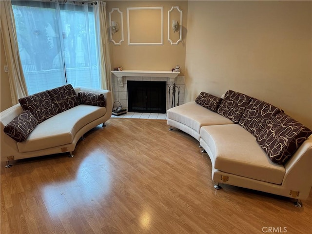 living room with a tiled fireplace and wood finished floors