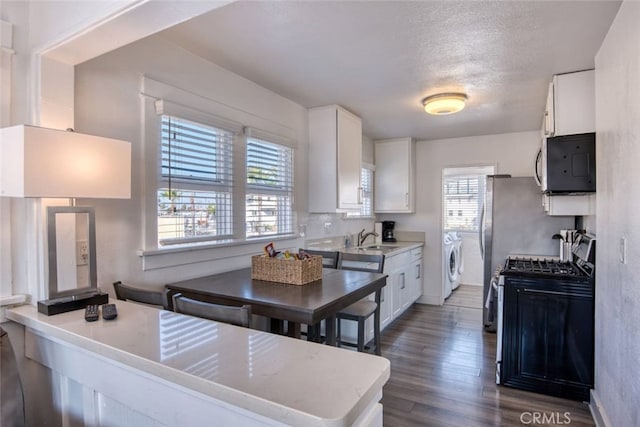 kitchen with stainless steel appliances, white cabinetry, sink, and washer and clothes dryer