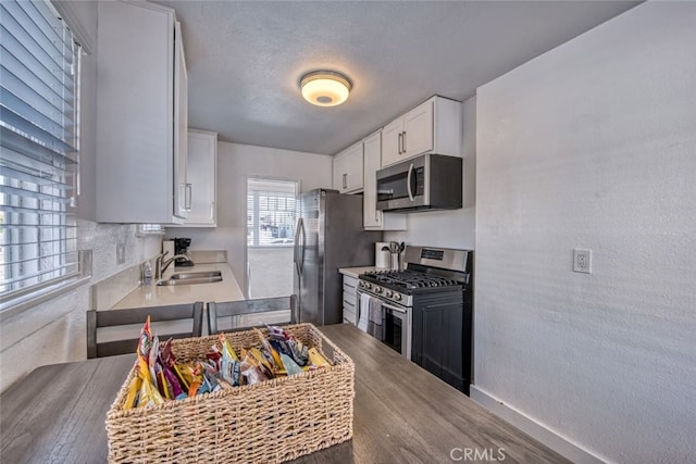 kitchen with stainless steel appliances, white cabinetry, sink, and a textured ceiling