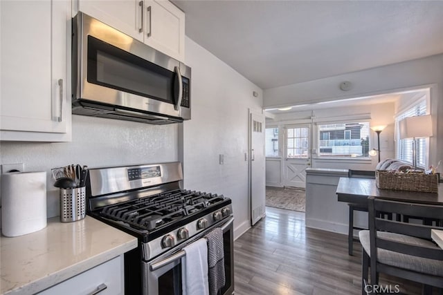 kitchen with white cabinetry, dark hardwood / wood-style flooring, light stone countertops, and appliances with stainless steel finishes