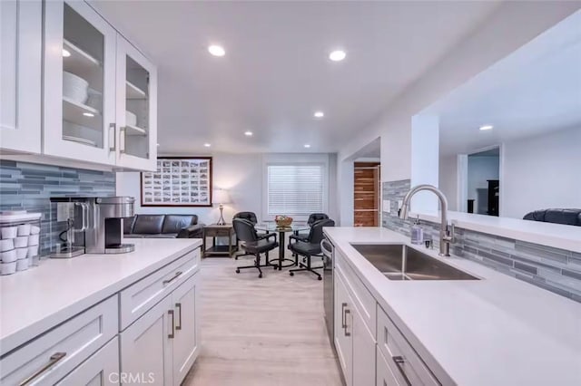 kitchen with sink, decorative backsplash, white cabinets, and light wood-type flooring