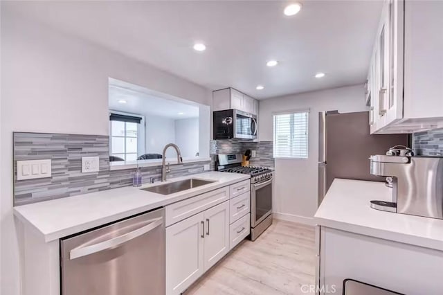 kitchen featuring appliances with stainless steel finishes, sink, white cabinets, and decorative backsplash