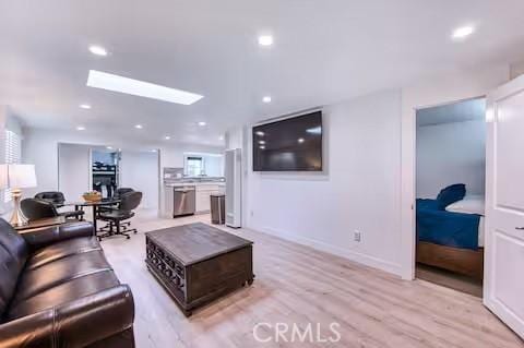 living room with light hardwood / wood-style floors and a skylight