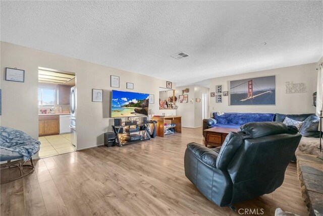 living room featuring a textured ceiling and light wood-type flooring