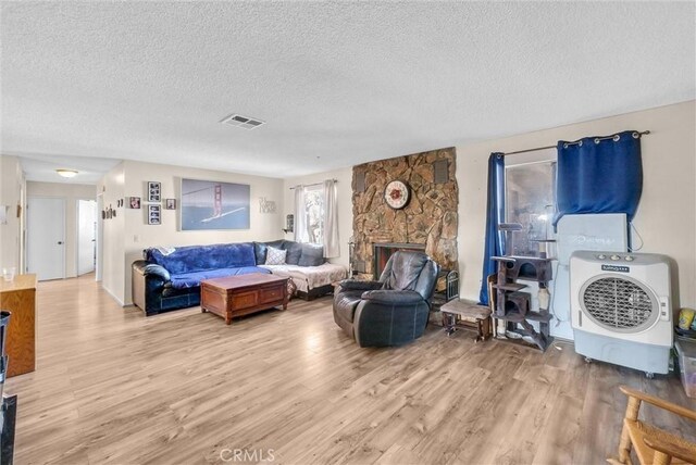 living room featuring a fireplace, light hardwood / wood-style floors, and a textured ceiling