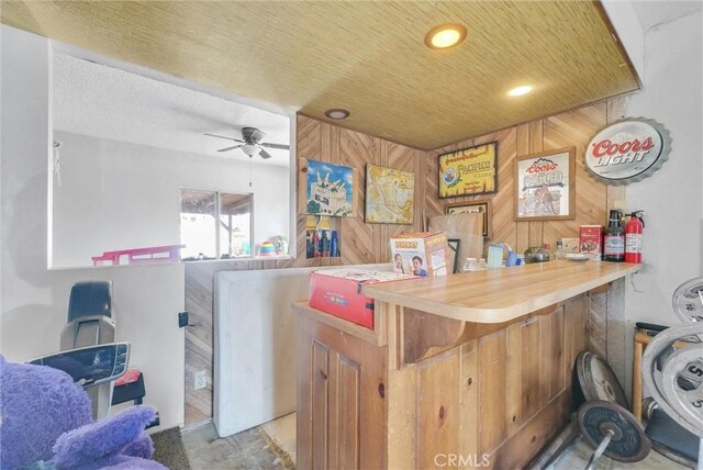 bar with ceiling fan and wood walls