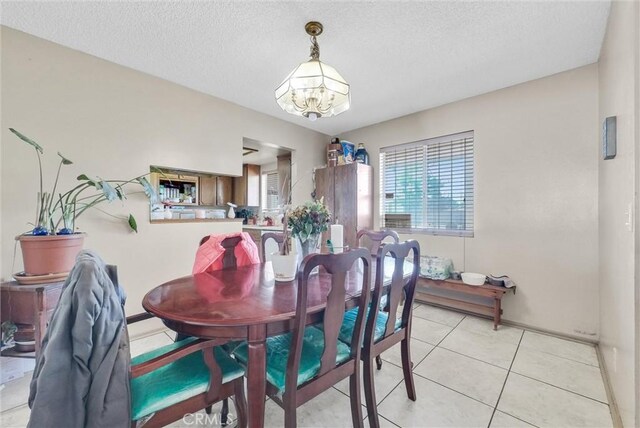 tiled dining area with a textured ceiling and a chandelier