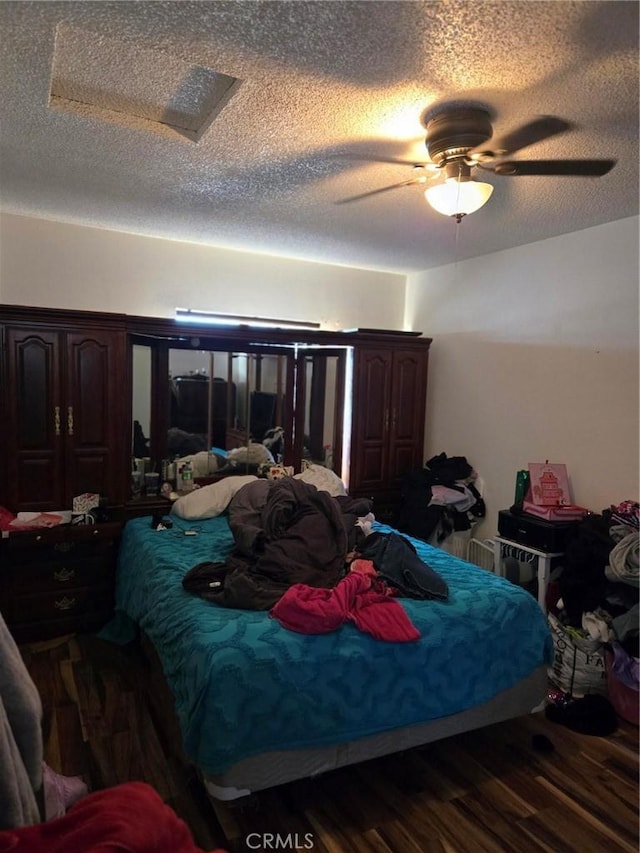 bedroom with a textured ceiling, dark wood-type flooring, and ceiling fan