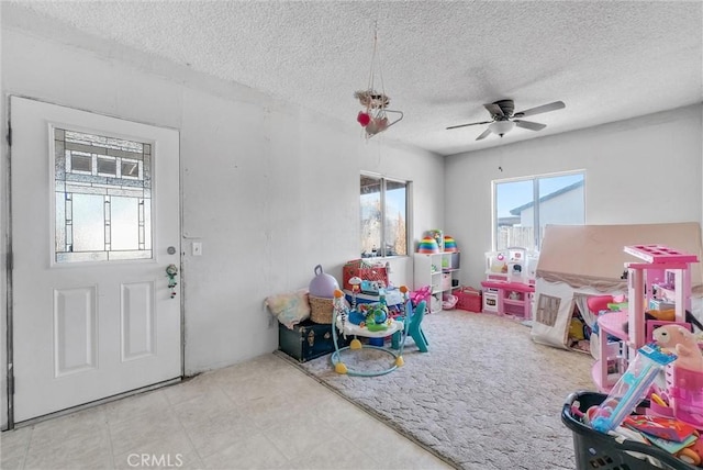 playroom with ceiling fan and a textured ceiling