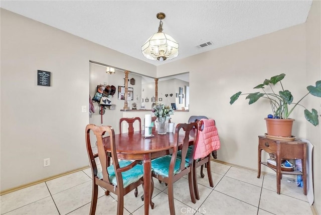 dining space with light tile patterned flooring, a notable chandelier, and a textured ceiling