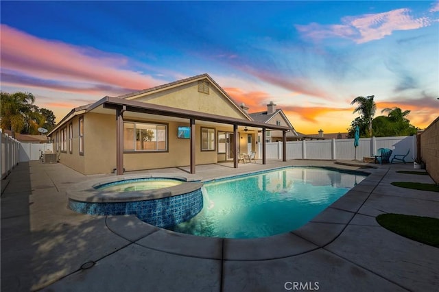 pool at dusk with a patio, central air condition unit, and an in ground hot tub