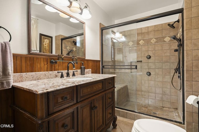 bathroom with a shower with shower door, wood walls, vanity, toilet, and tile patterned floors