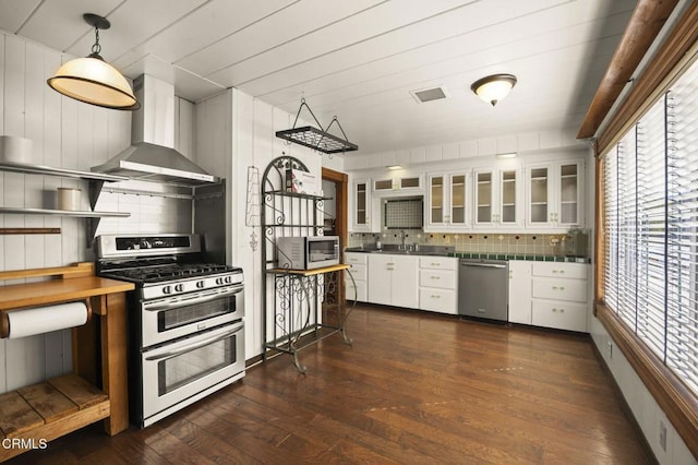 kitchen featuring white cabinetry, backsplash, stainless steel appliances, dark hardwood / wood-style floors, and wall chimney exhaust hood