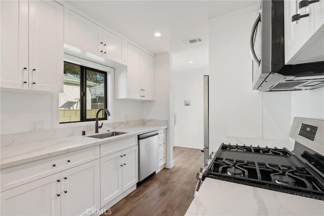 kitchen featuring appliances with stainless steel finishes, sink, white cabinets, dark hardwood / wood-style flooring, and light stone countertops