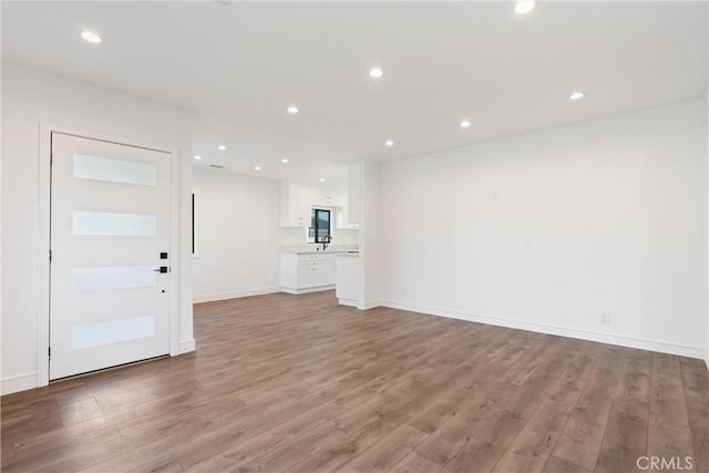 unfurnished living room featuring sink and light hardwood / wood-style floors