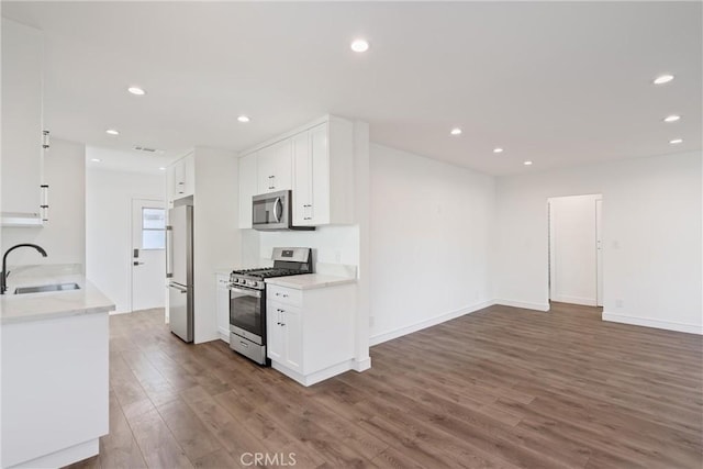 kitchen with dark wood-type flooring, stainless steel appliances, sink, and white cabinets