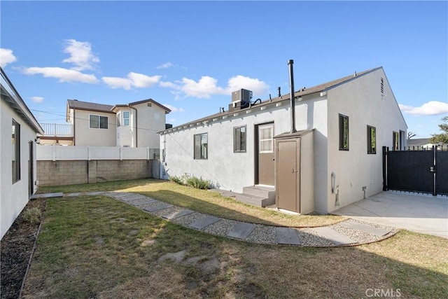 back of house featuring a yard and central AC