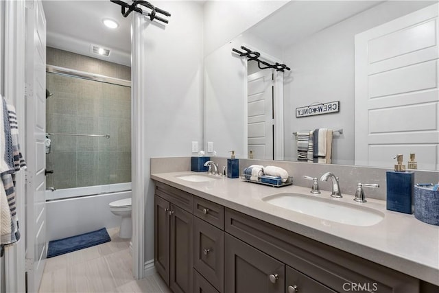 full bathroom featuring toilet, vanity, and shower / bath combination with glass door