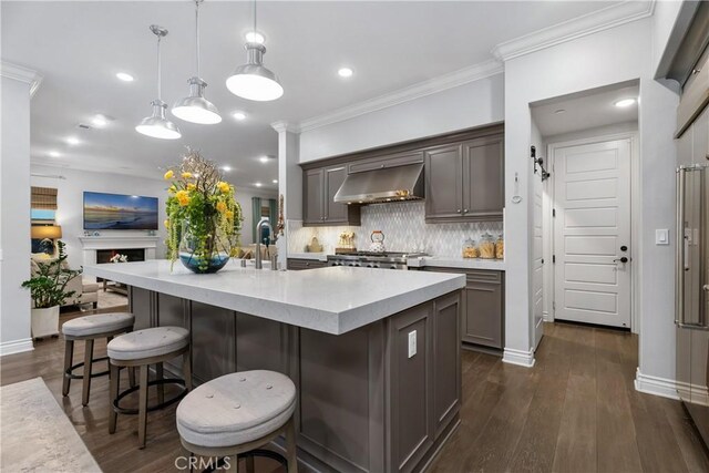 kitchen with a spacious island, a kitchen breakfast bar, range hood, and hanging light fixtures