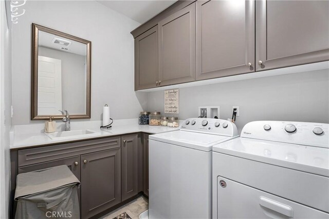 laundry area with cabinets, separate washer and dryer, and sink